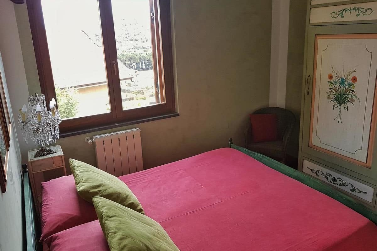 Ein Schlafzimmer mit Bett, Heizkörper, Fenster und Schrank.
