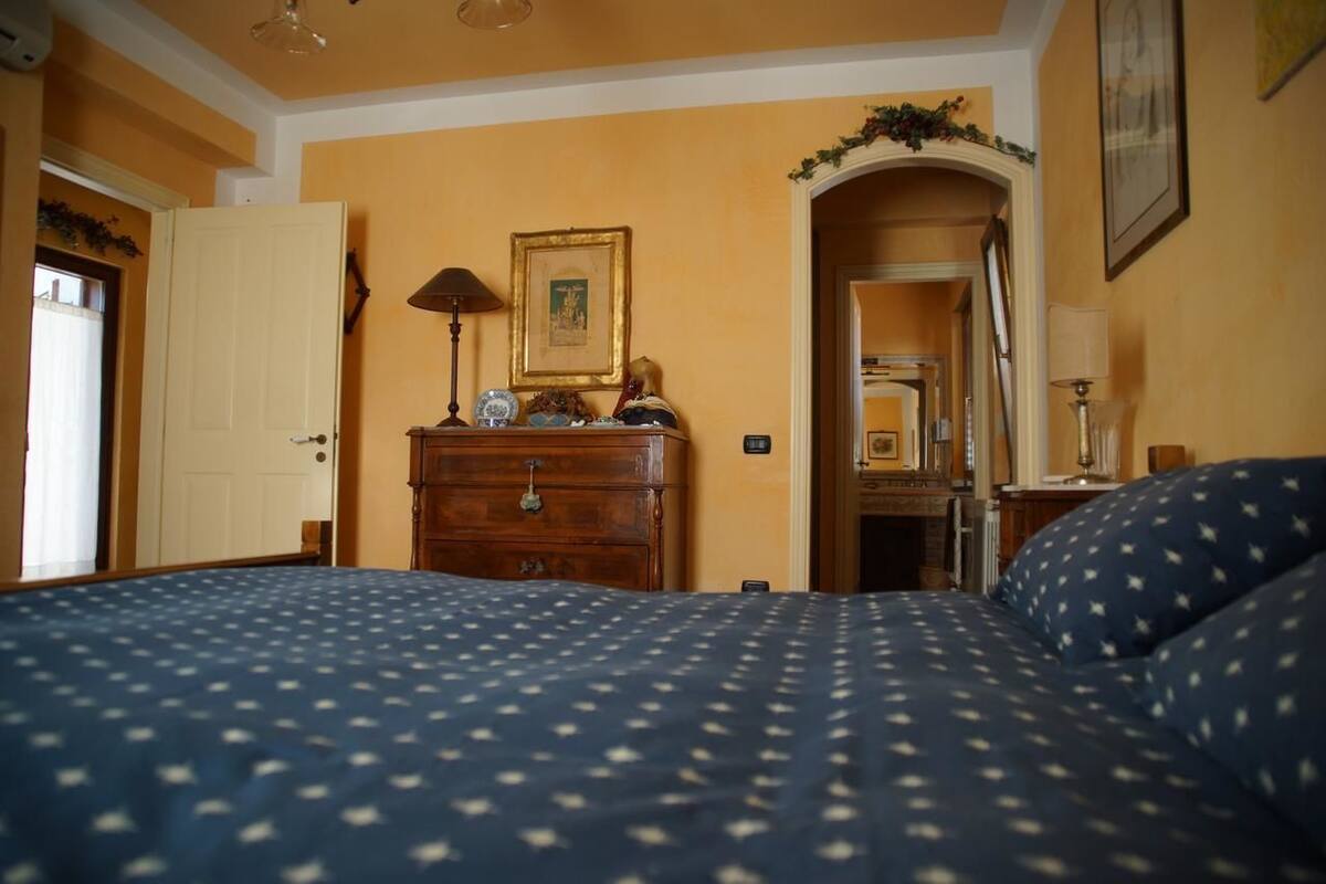 Ein Schlafzimmer mit Bett, Schminktisch und einer Tür zu einem weiteren Raum.