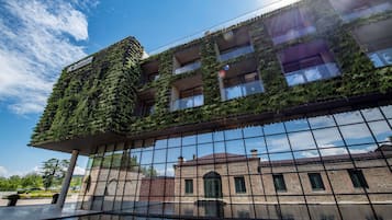 Surrounded by lush greenery, this building features multiple balconies with plants and a serene reflective pool.