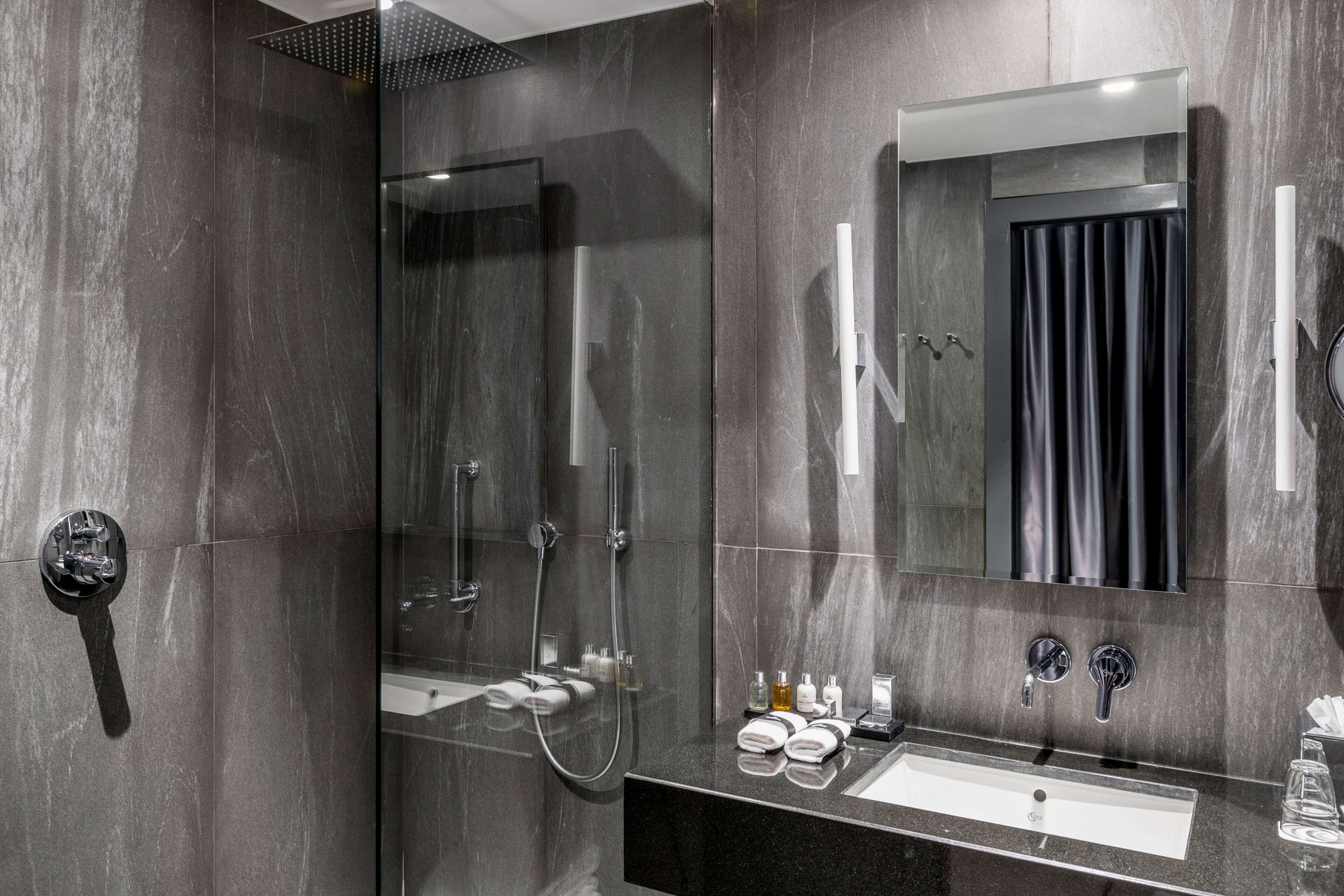 A modern bathroom with a glass-enclosed shower, a vanity with a mirror, and a sink.