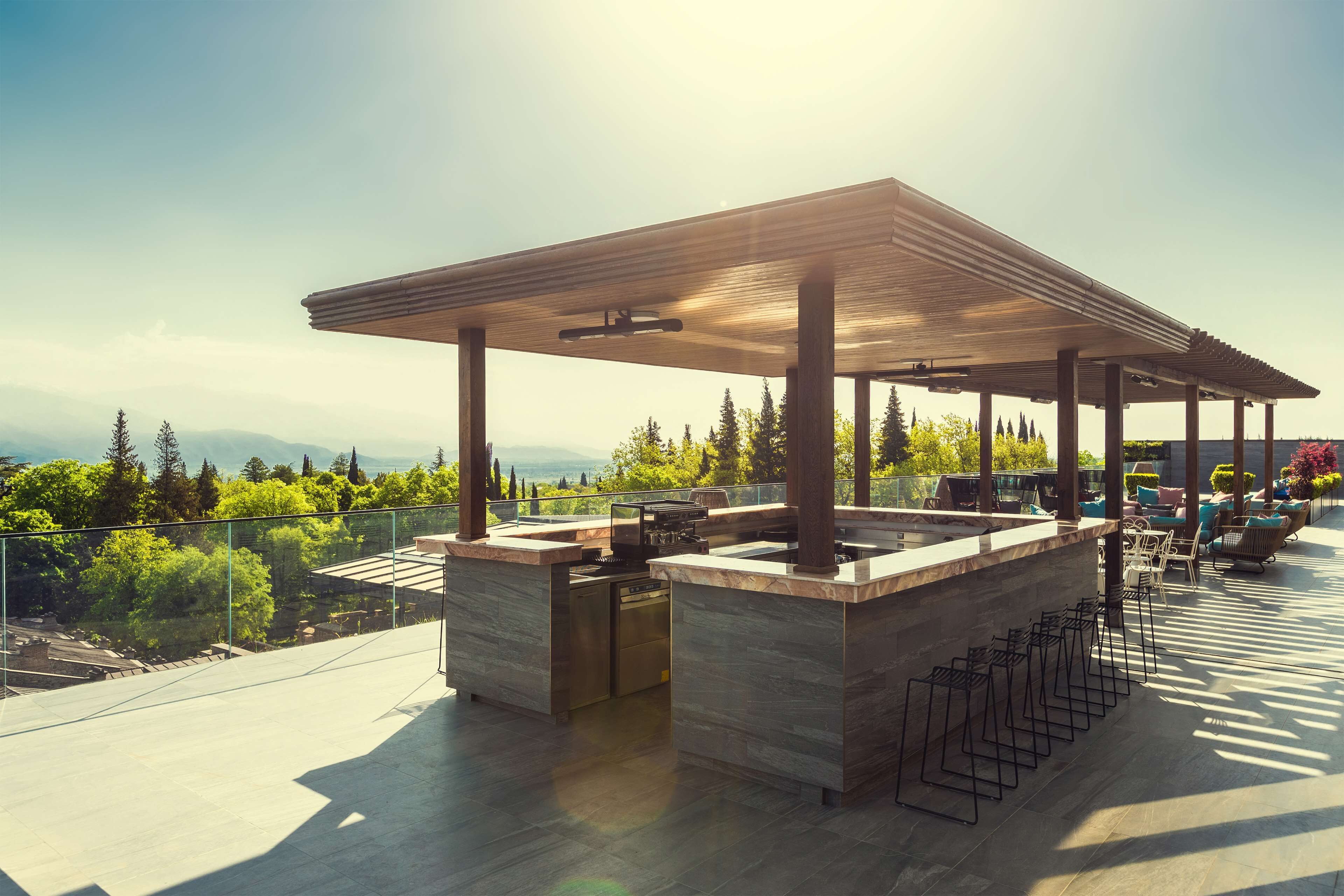 An outdoor kitchen area with a pergola, built-in bar, and seating.