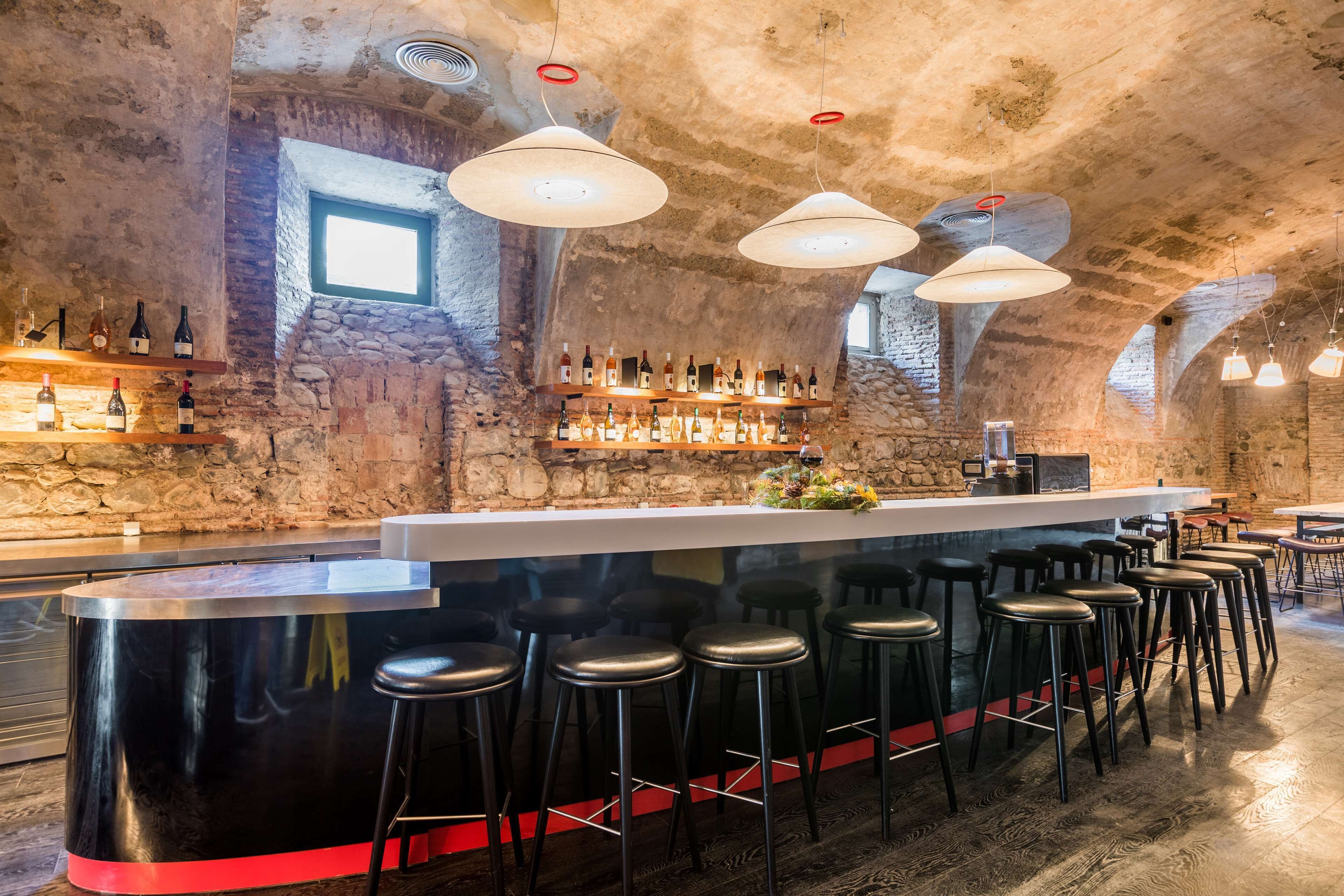 A bar area with a stone wall backdrop, a bar counter, and multiple stools.