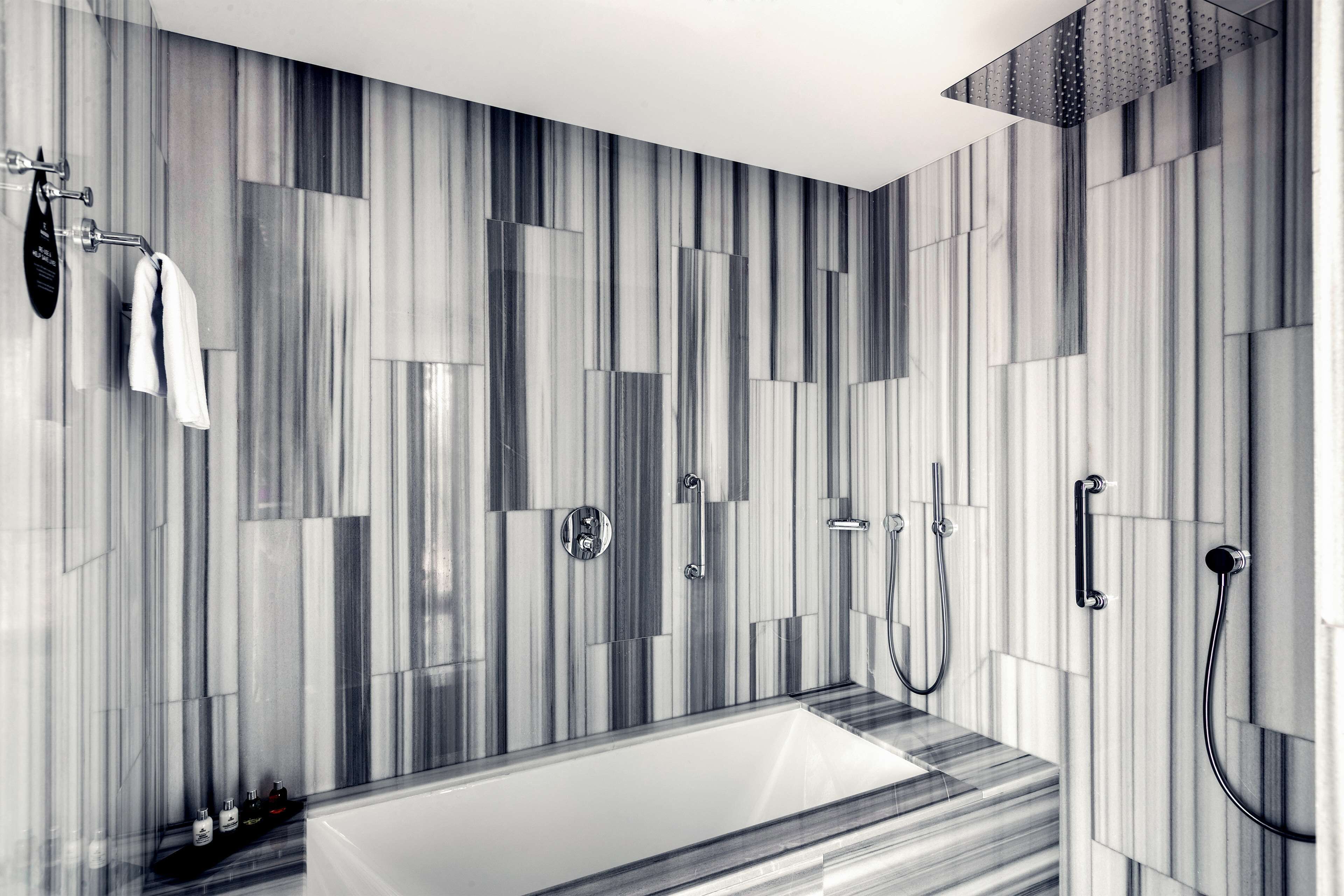 Une salle de bain moderne dotée d’une grande baignoire, d’un espace douche et d’un porte-serviettes avec des serviettes.