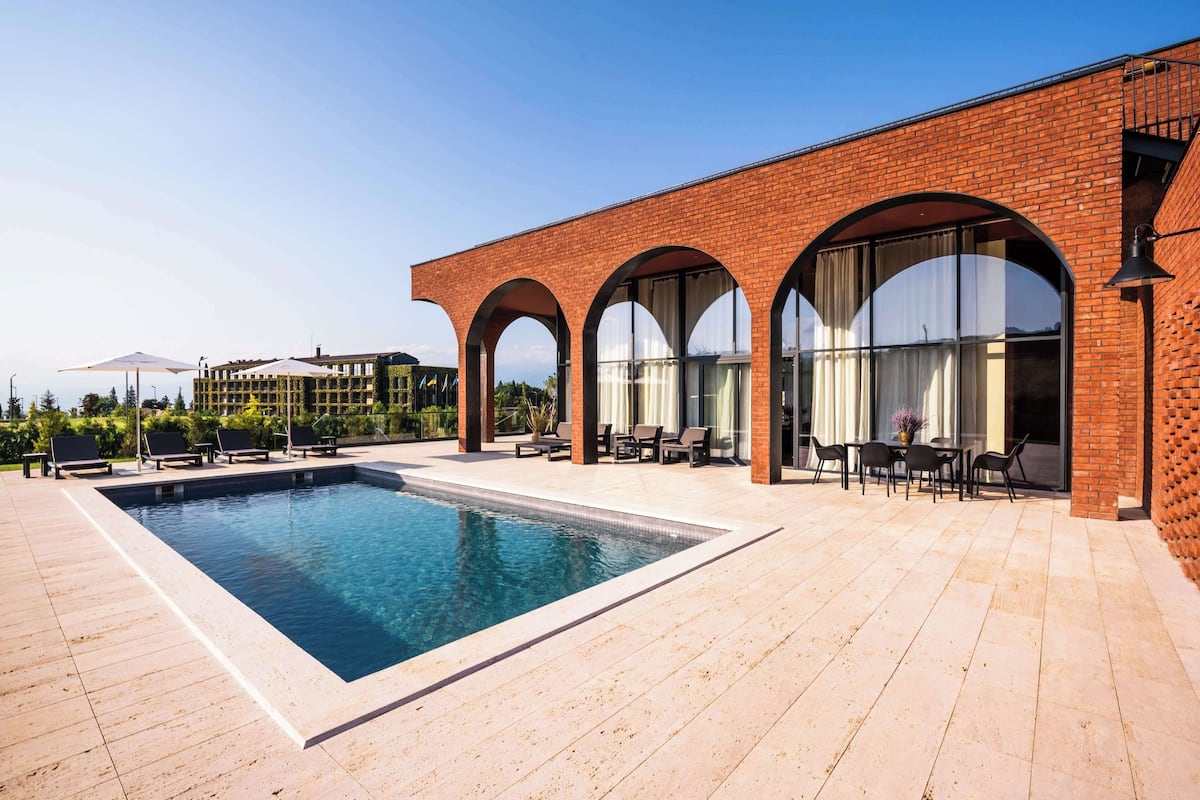 A swimming pool with lounge chairs and a patio area with tables and chairs.
