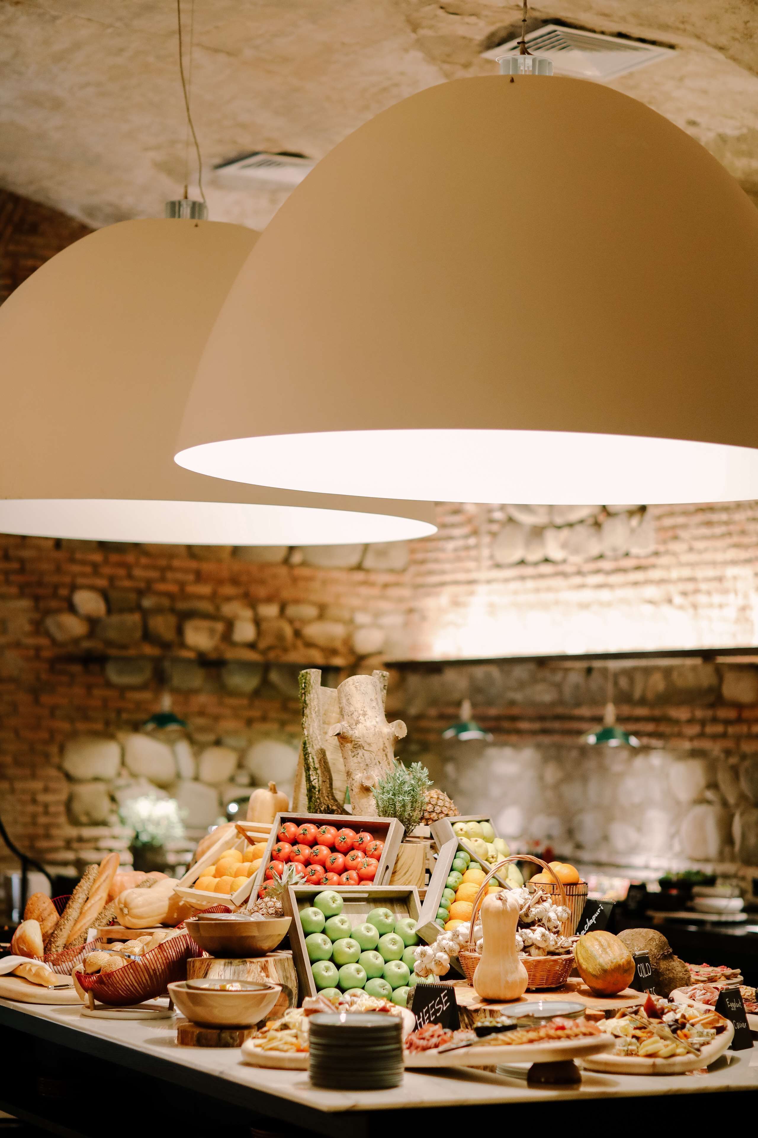 A buffet with various food items and a stone wall background.