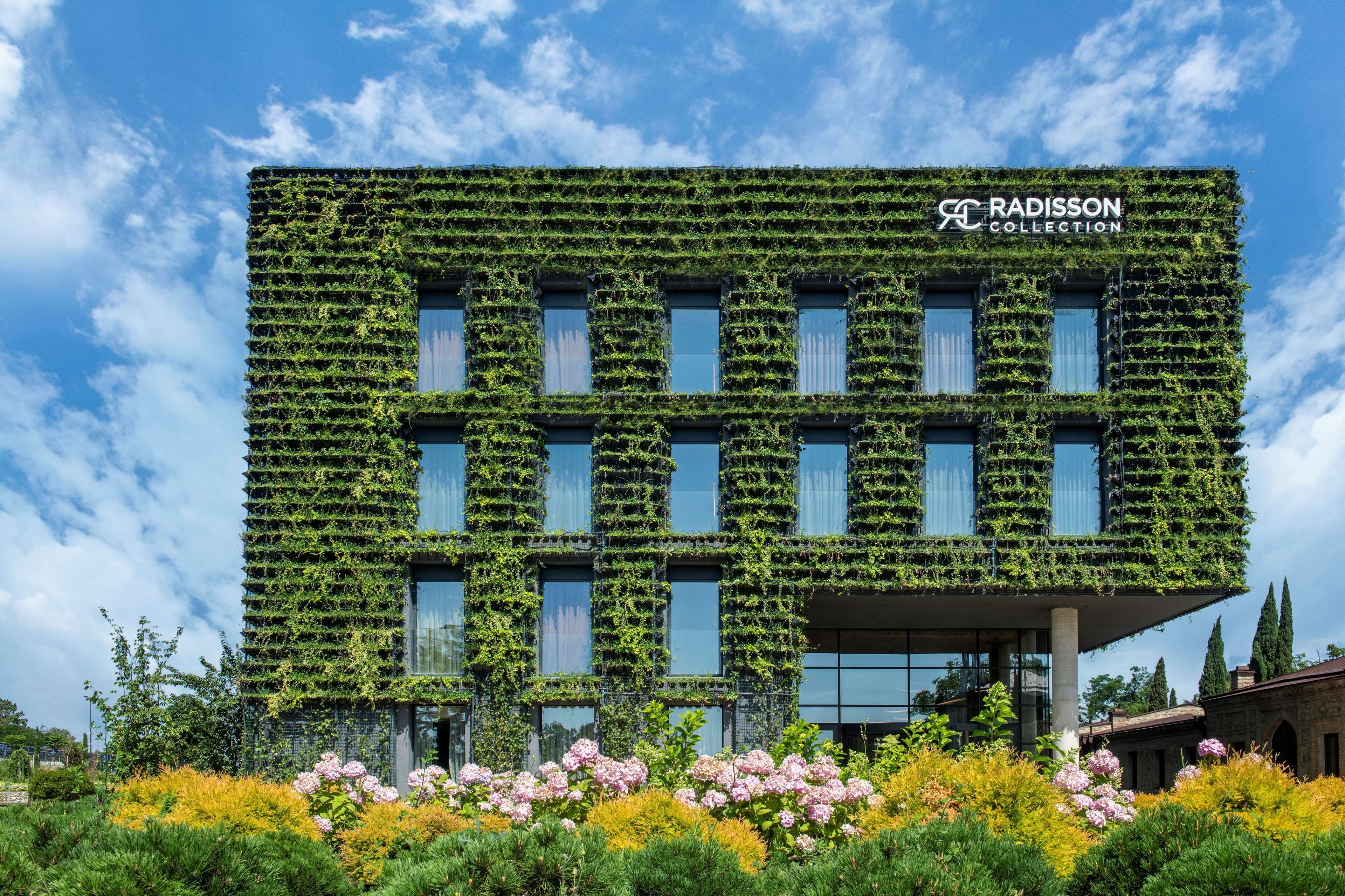 Un bâtiment moderne à la façade verdoyante, recouverte de plantes, portant l’inscription « RADISSON COLLECTION ».