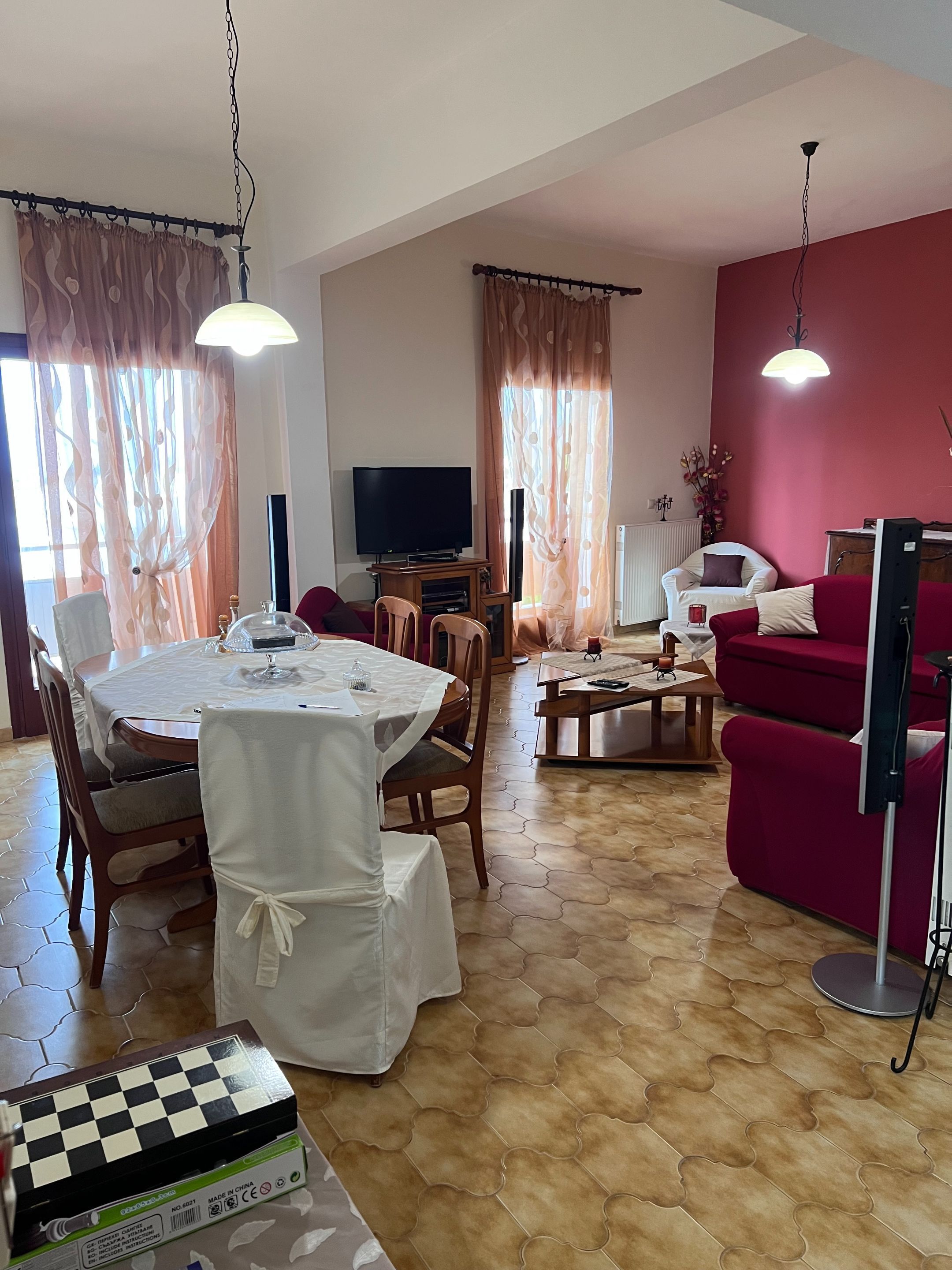 A living room with a dining area, a TV, and a red wall.