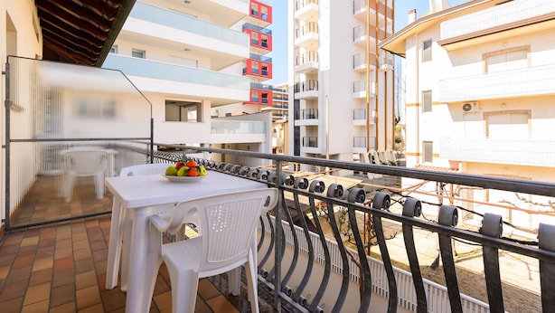 Ein Balkon mit Tisch und Stühlen mit Blick auf ein Wohngebiet mit mehrstöckigen Gebäuden.