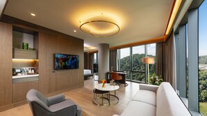 Une chambre d’hôtel moderne dotée d’une grande fenêtre, d’un téléviseur à écran plat, d’un coin repas et d’un canapé.