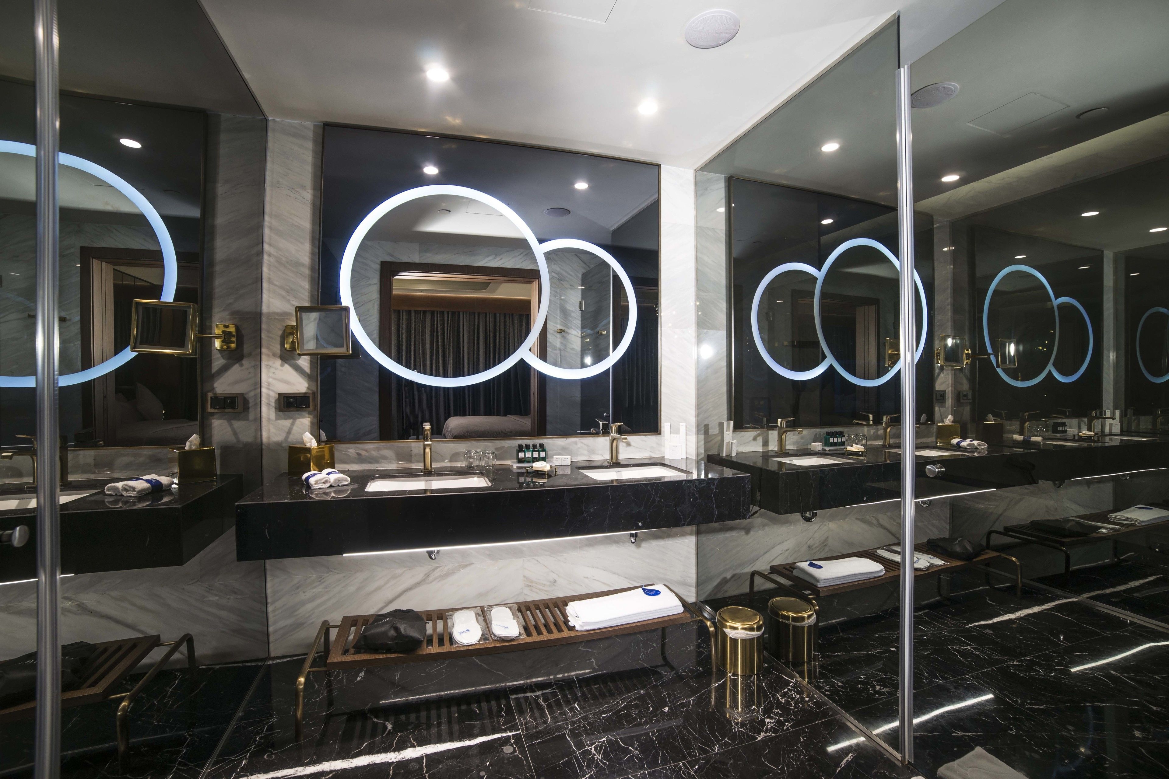 A modern bathroom with multiple sinks, marble countertops, and circular mirrors.