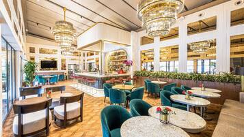 A spacious hotel lobby with high ceilings, multiple seating areas, and a bar.