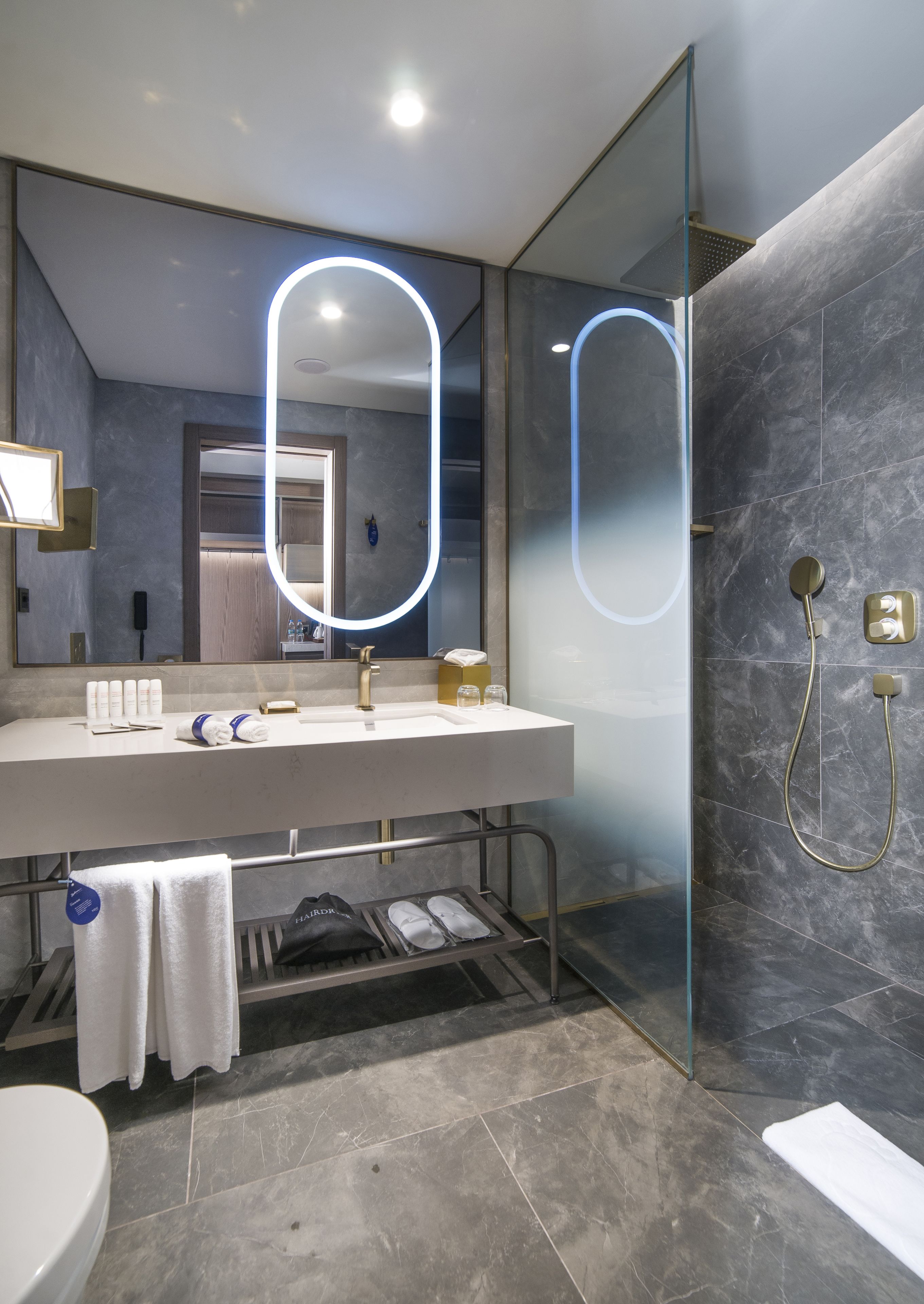 Un baño moderno con un espejo grande, un lavabo y una ducha.