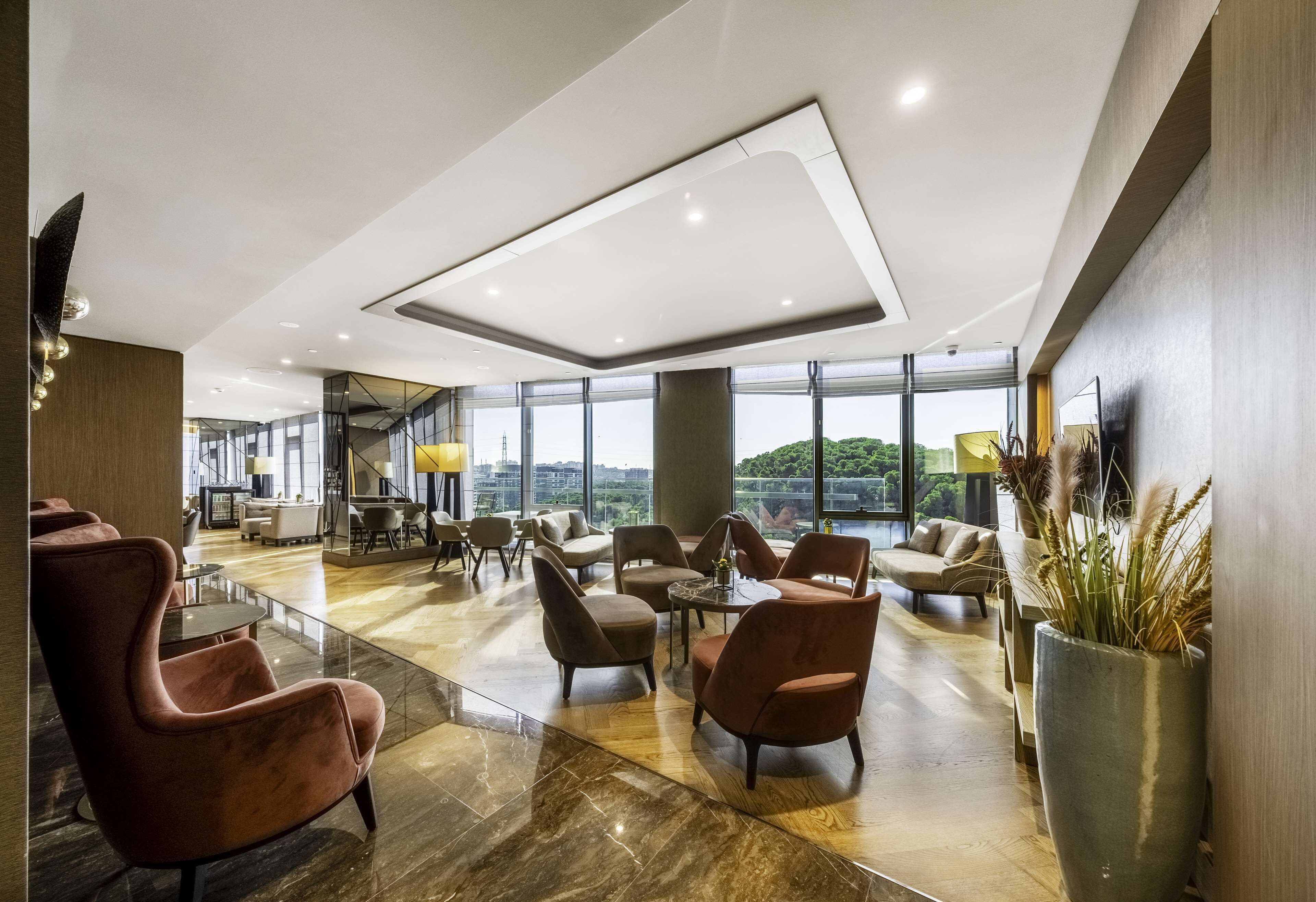 A spacious lobby with modern furniture, large windows, and a view of the city.
