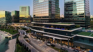 Un immeuble moderne à plusieurs étages, doté d’une façade en verre, entouré d’autres gratte-ciel.