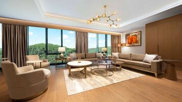 A spacious living room with a large window, a modern chandelier, and a view of a green landscape.