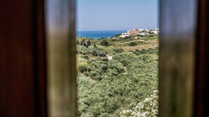 Vista a través de una ventana de un paisaje costero con edificios al fondo.
