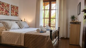 Un dormitorio con cama, almohadas, un armario de madera y una ventana con cortinas.