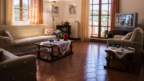 Una sala de estar con dos sofás, una mesa de centro, un televisor y un amplio ventanal con cortinas.