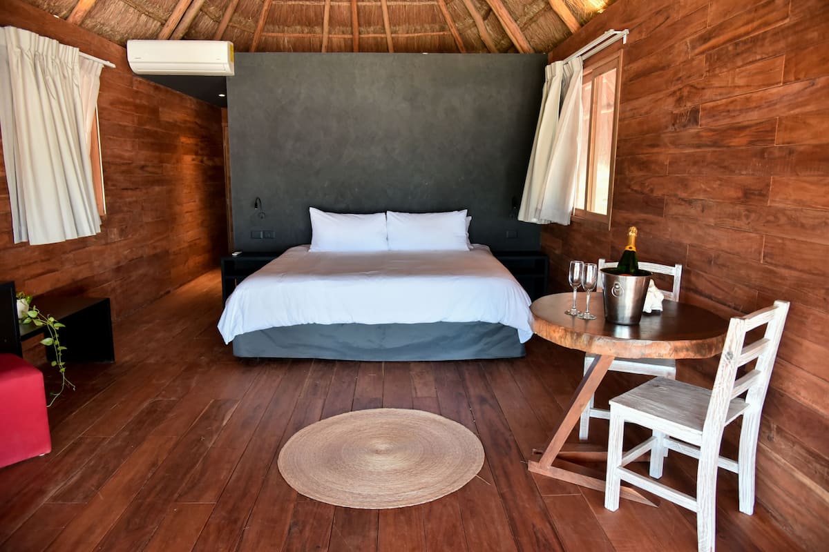 Une chambre avec un grand lit, une petite table avec des chaises et un tapis rond.