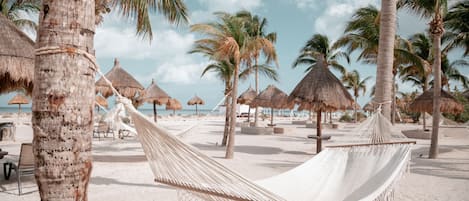 Een privéstrand, wit zand, ligstoelen aan het strand, strandlakens