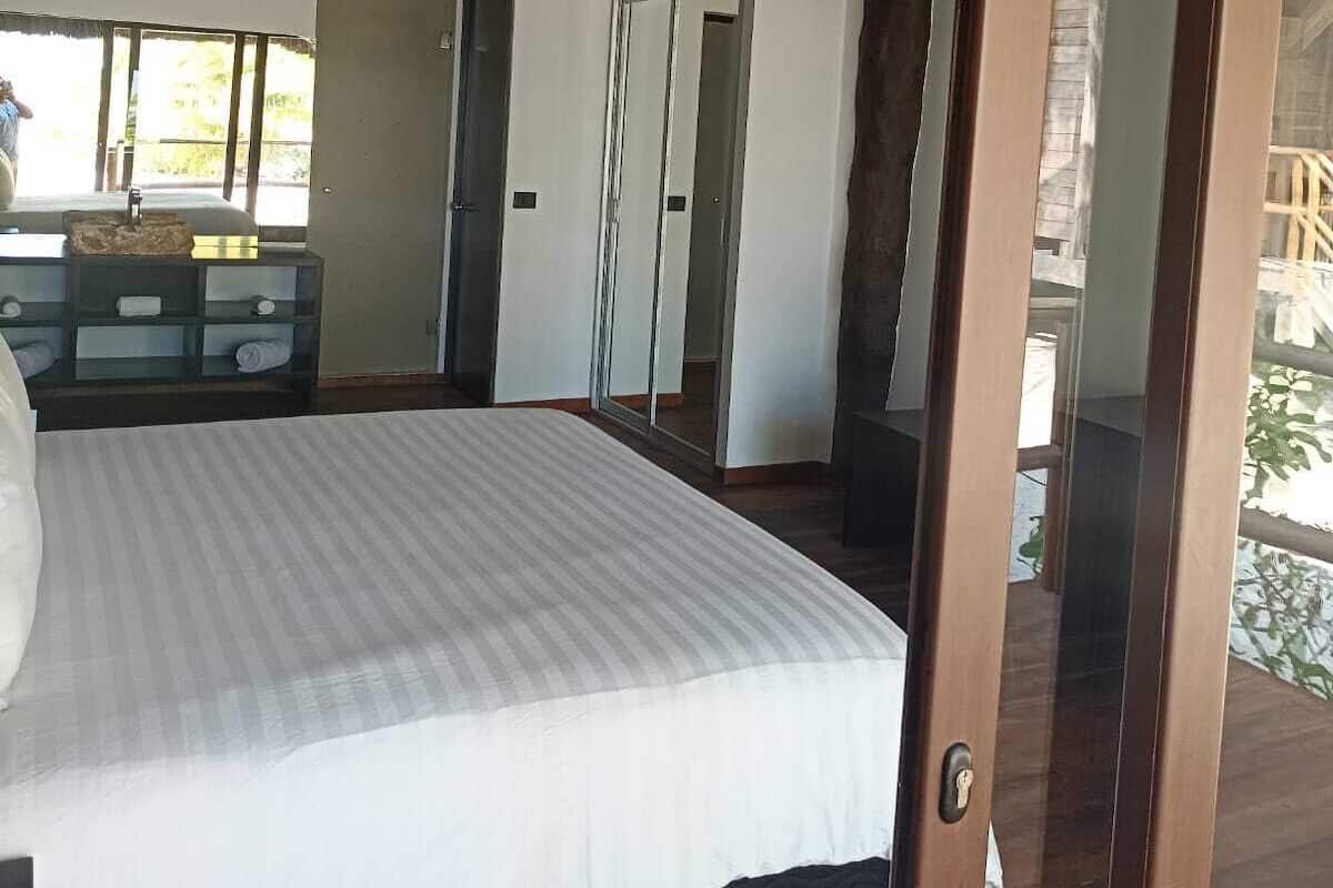 Une chambre avec un grand lit, une porte en bois et une vue sur l’extérieur.