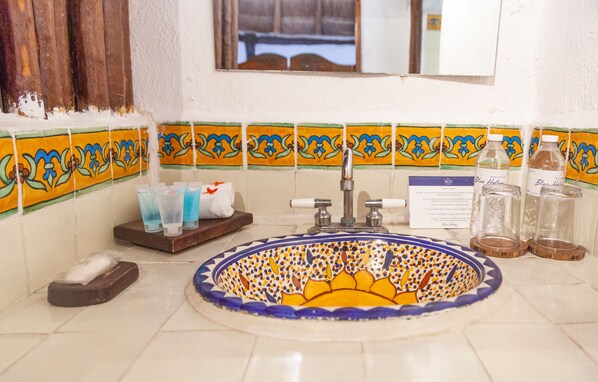 Un baño con un lavamanos decorativo, una ventana y un salpicadero de azulejos.