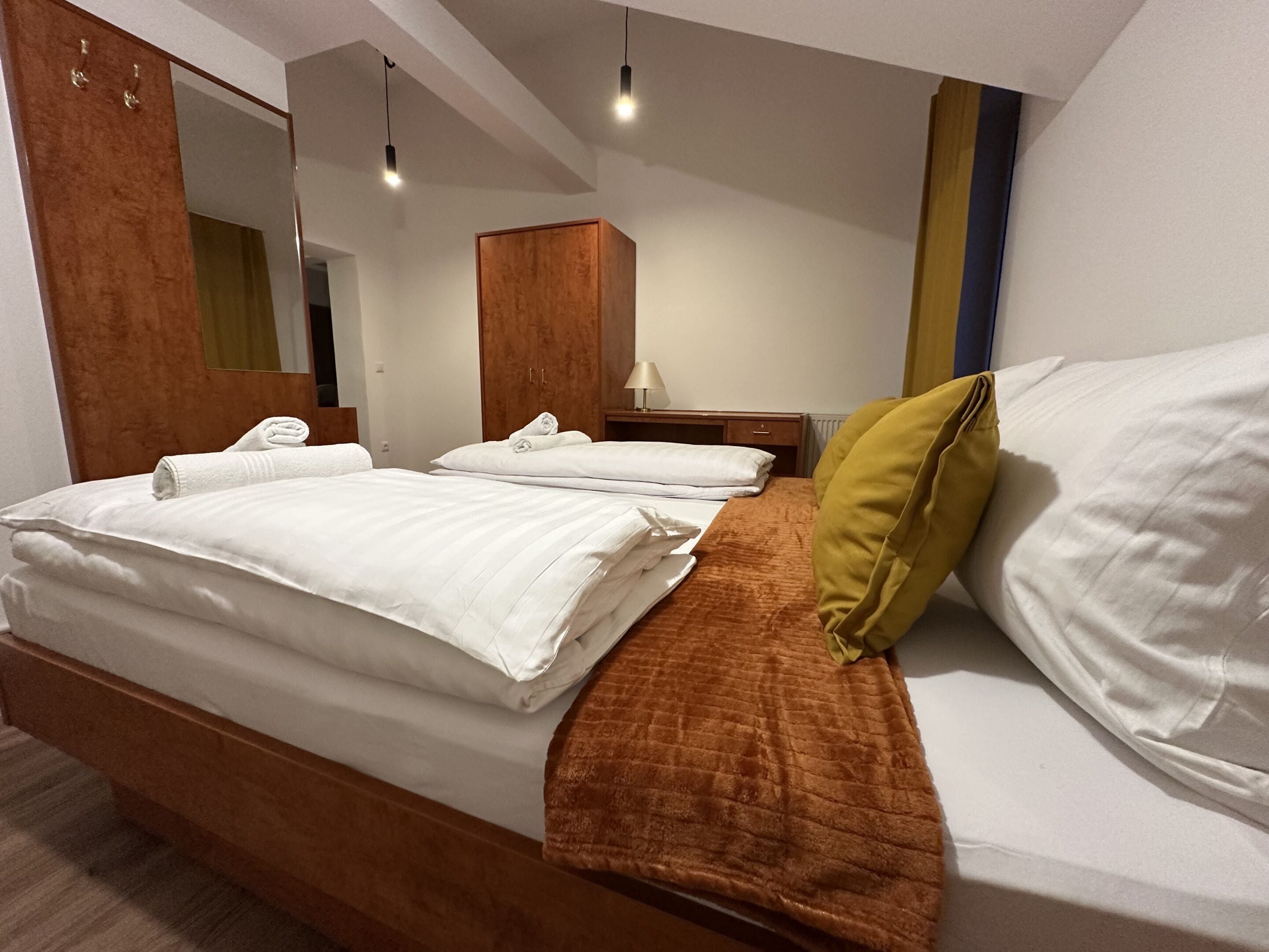 Ein Hotelzimmer mit einem Bett, einem Nachttisch, einer Lampe, einem Spiegel und einem Holzschrank.