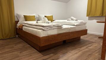 Un lit bien fait, avec une literie blanche et deux oreillers, une tête de lit en bois et un plancher en bois.