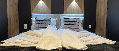 A bed with a headboard, two pillows, and a blanket.