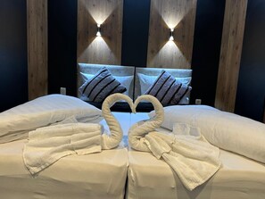 A hotel room with a bed, two wall-mounted lights, and a heart-shaped towel arrangement. - Apartmenthaus Zeuthen 1 (Zeuthen)