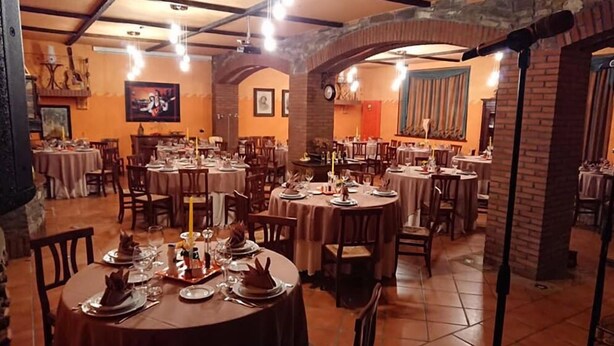 A restaurant with multiple round tables set for dining, featuring a brick archway and warm lighting. - Agriturismo Alpi (Roccaforte Ligure)