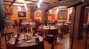 A restaurant with multiple round tables set for dining, featuring a brick archway and warm lighting. - Agriturismo Alpi (Roccaforte Ligure)
