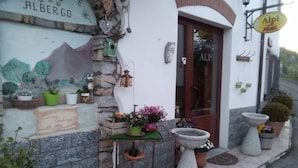 A building with a stone facade, a wooden door, and a sign reading "Alpi." - Agriturismo Alpi (Roccaforte Ligure)
