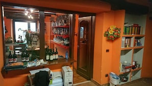 A room with a wooden door, a mirror, shelves with bottles, and a bookshelf. - Agriturismo Alpi (Roccaforte Ligure)
