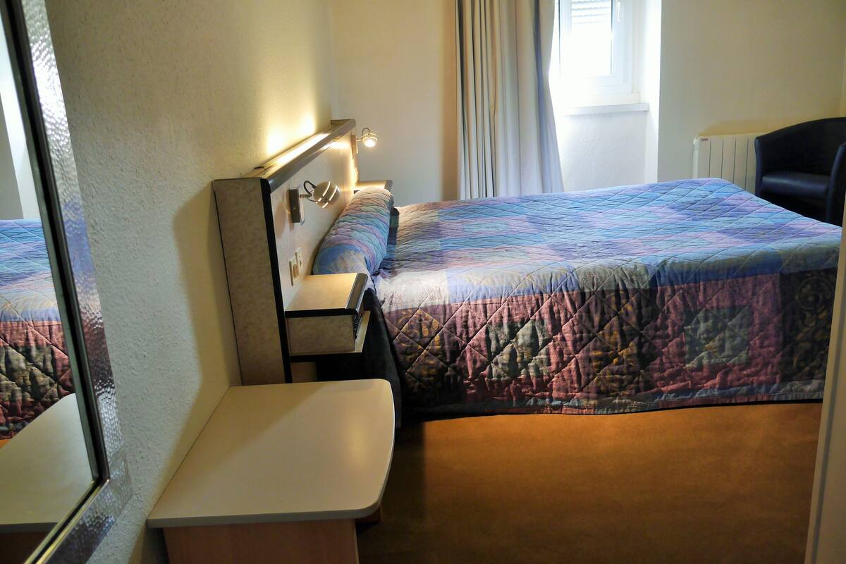 A hotel room with two beds, a desk, a chair, and a window with curtains.