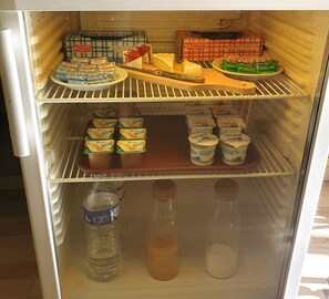 A refrigerator with multiple shelves containing various food items and containers. - Hôtel Terminus (Saint-Malo)