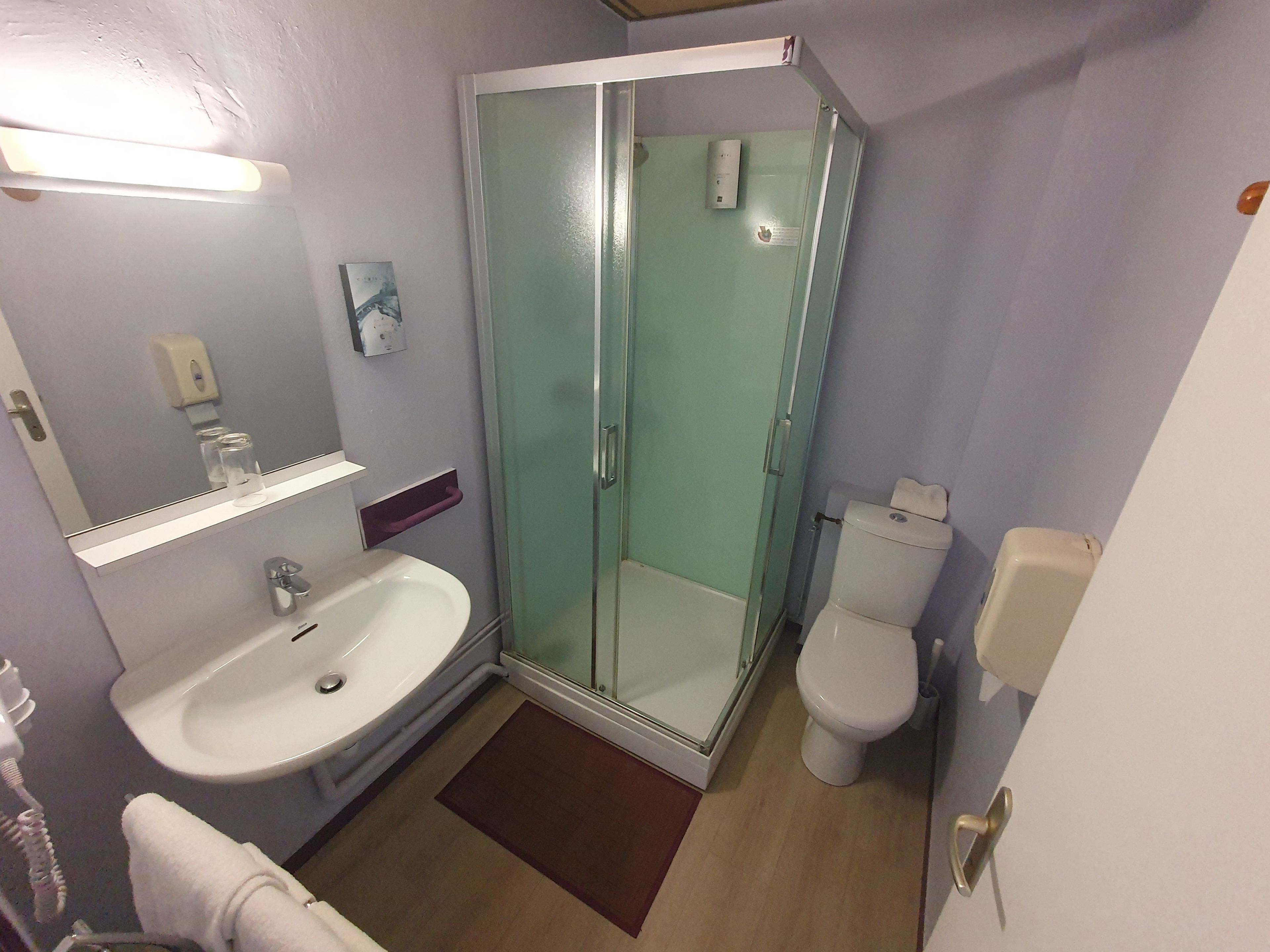 A bathroom with a glass-enclosed shower, a white sink, and a toilet.
