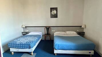 Ein Hotelzimmer mit zwei Einzelbetten, einem Sessel und einem Wandbild.