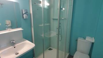 Une salle de bain avec une douche à parois de verre, un lavabo et des toilettes.