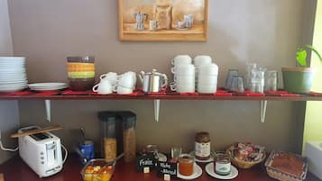 Een ontbijtbuffet met diverse etenswaren, bestek en een schilderij aan de muur.
