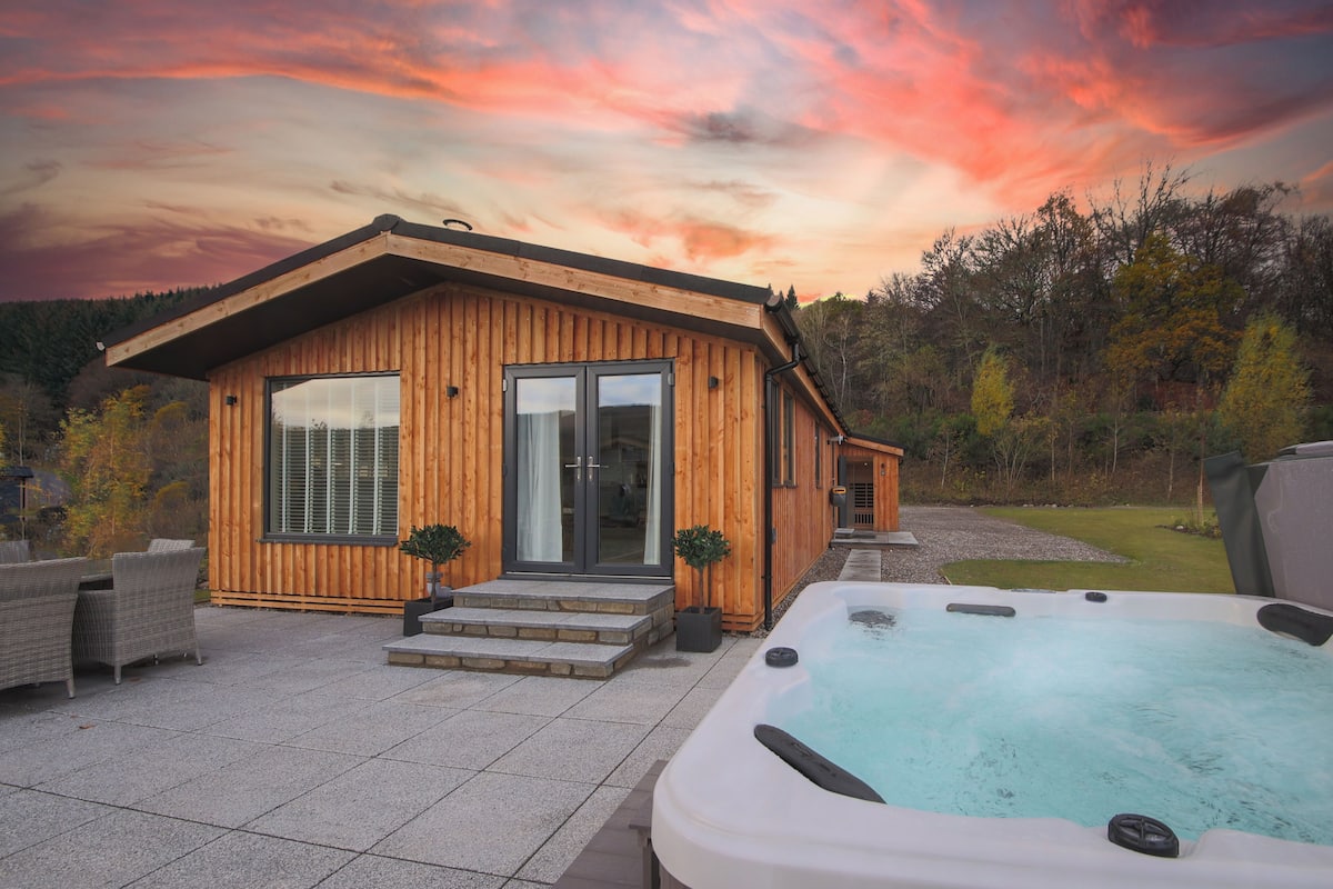 Una cabaña de madera con jacuzzi y zona de patio.