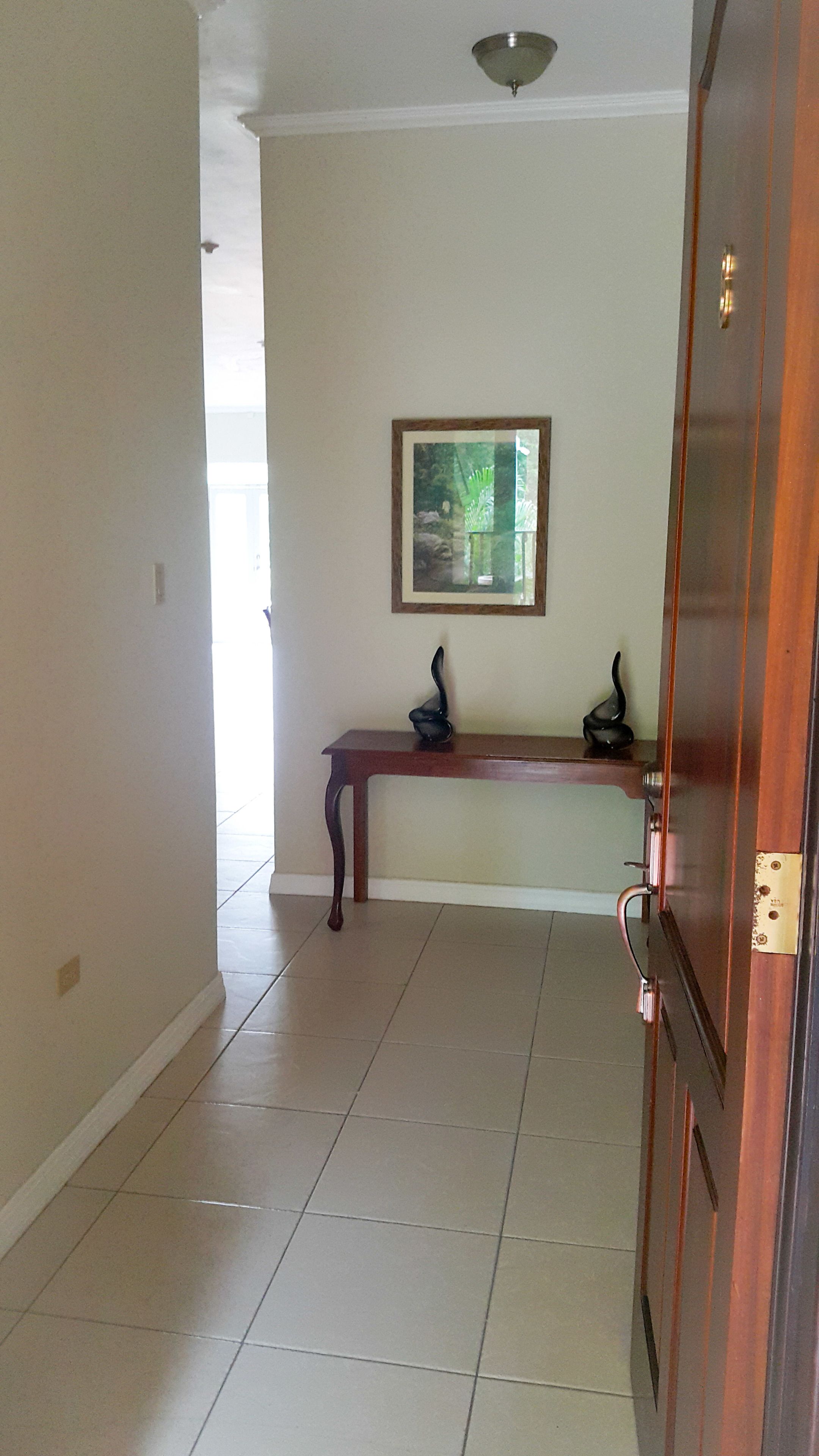 A hallway with a wooden bench, a framed picture on the wall, and a door.