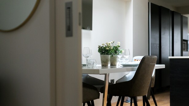 A modern dining area with a white table, two chairs, and a potted plant. - D'Arblay Street (London)