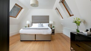 A modern bedroom with a bed, bedside tables, a dresser, and a skylight. - D'Arblay Street (London)