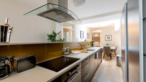 A modern kitchen with a glass hood, stainless steel appliances, and a dining area with a table and chairs. - D'Arblay Street (London)