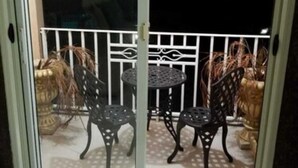 A sliding glass door leading to an outdoor patio with a table and two chairs. - The Hamptons of Acadia (Kingston)
