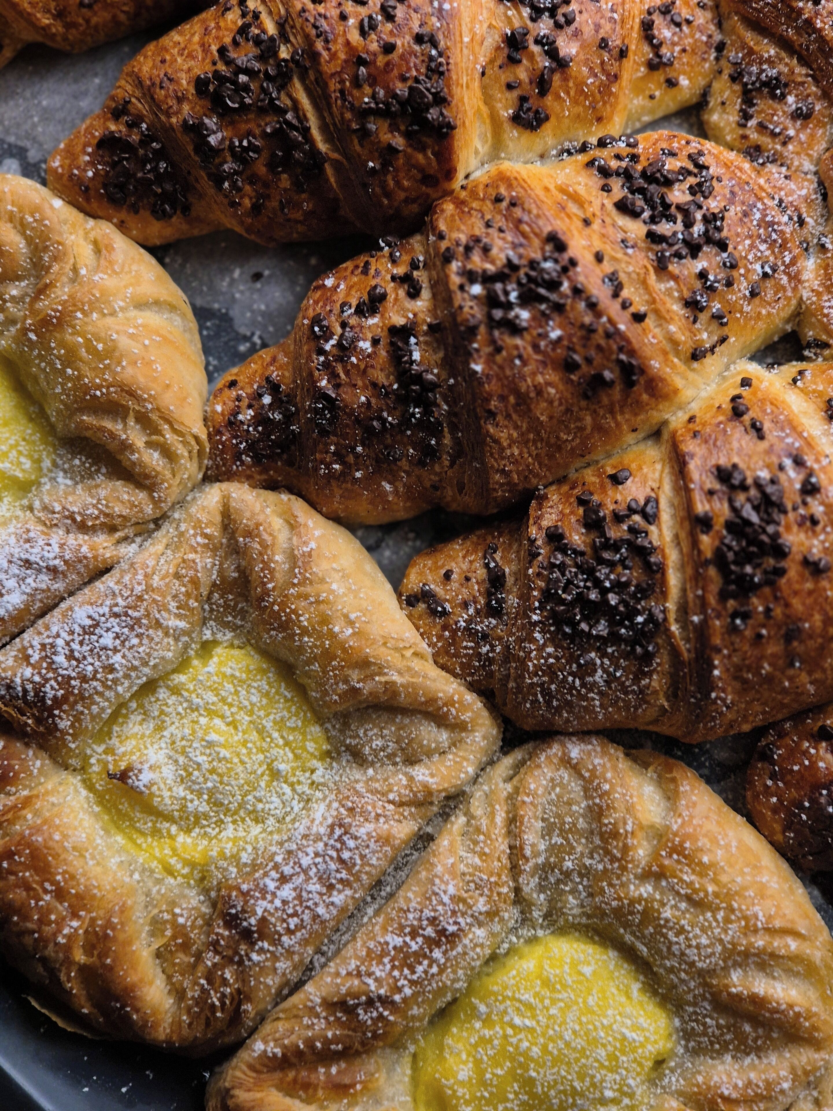 A variety of pastries, including croissants and puff pastries, arranged on a tray.