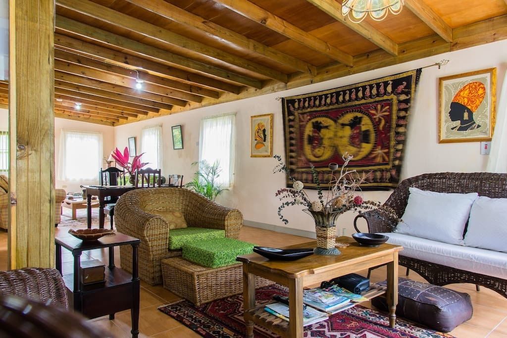 A cozy living room with wicker furniture, a wooden ceiling, and decorative tapestries.
