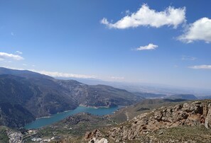A mountainous landscape with a lake and a town in the valley. - Casa Rural Arroyo de la Greda (Guejar Sierra)