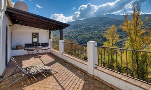 A balcony with a table and chairs, a bench, and a view of a mountainous landscape. - Casa Rural Arroyo de la Greda (Guejar Sierra)